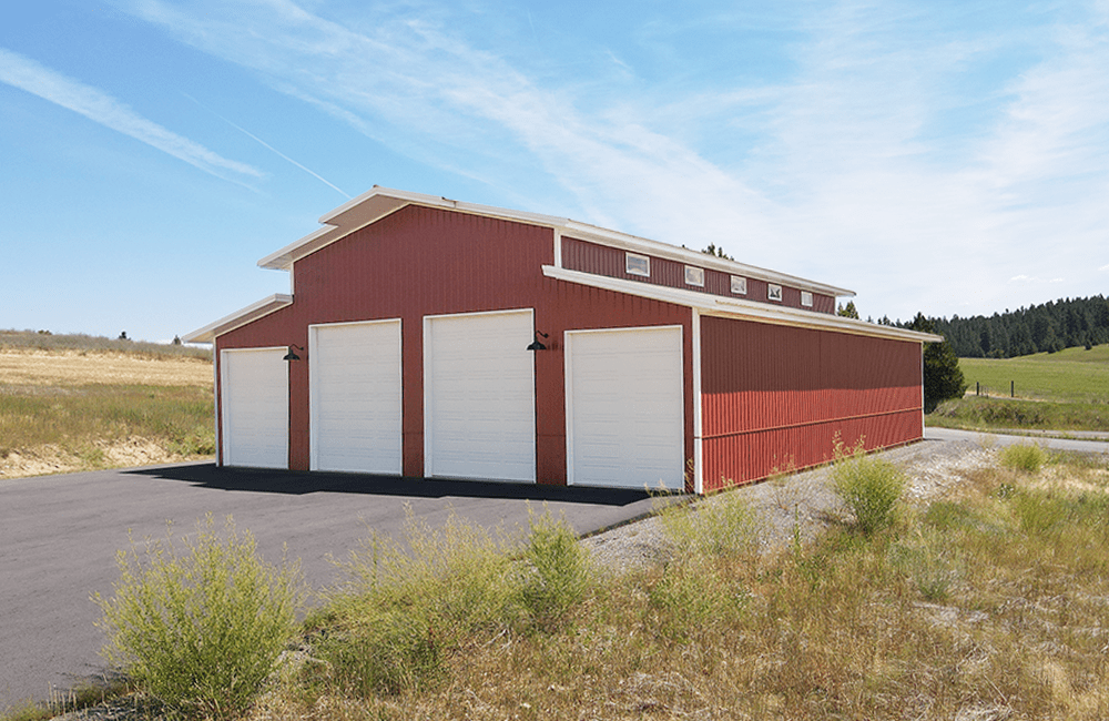 Red steel structure barn with white trim and 4 white over-head garage doors