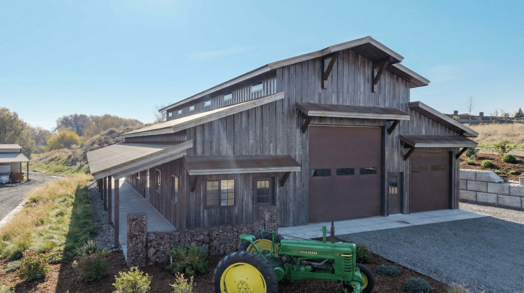 A rustic look barndominium with a tractor in front
