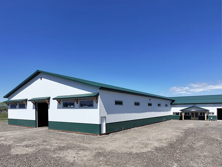 A metal agricultural and farm building. White siding with dark green accents
