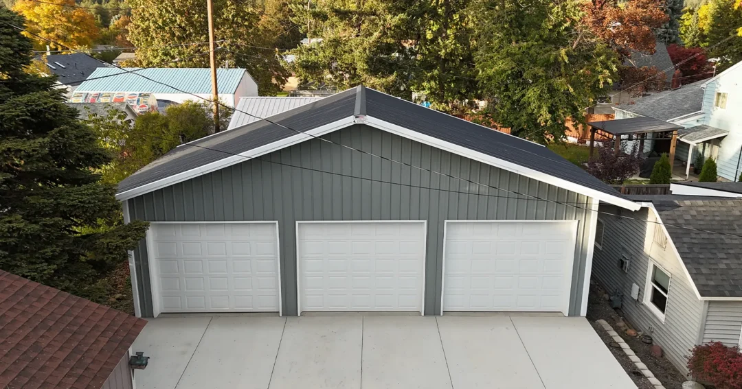 A 3 car pole barn garage that is grey and white in color