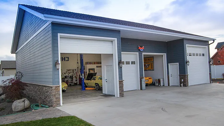 A garage shop combo with its overhead doors open showing the shop layout in the workshop area of the garage