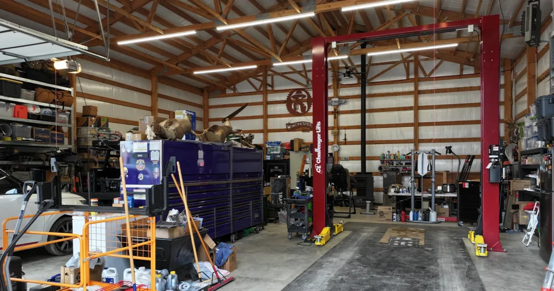 The interior of a pole barn garage and workshop combo building with a car lift and tools