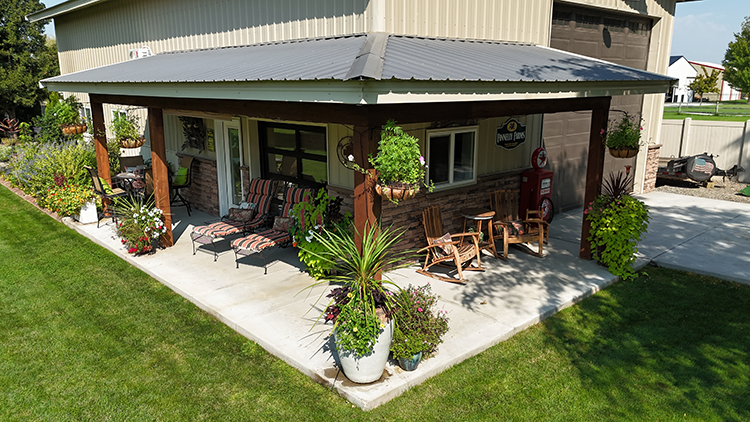 A pole barn has a beautiful lean-to porch complete with outdoor furniture and decorations