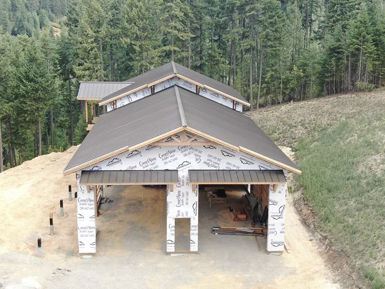 A pole barn is under construction and wrapped in a white vapor barrier to prevent condensation