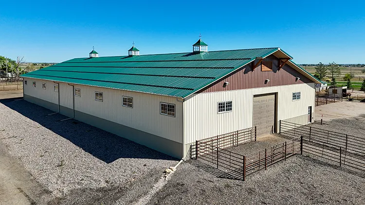 A 40X80 cattle barn agricultural pole barn. White walls, and green roof, steel post-frame building