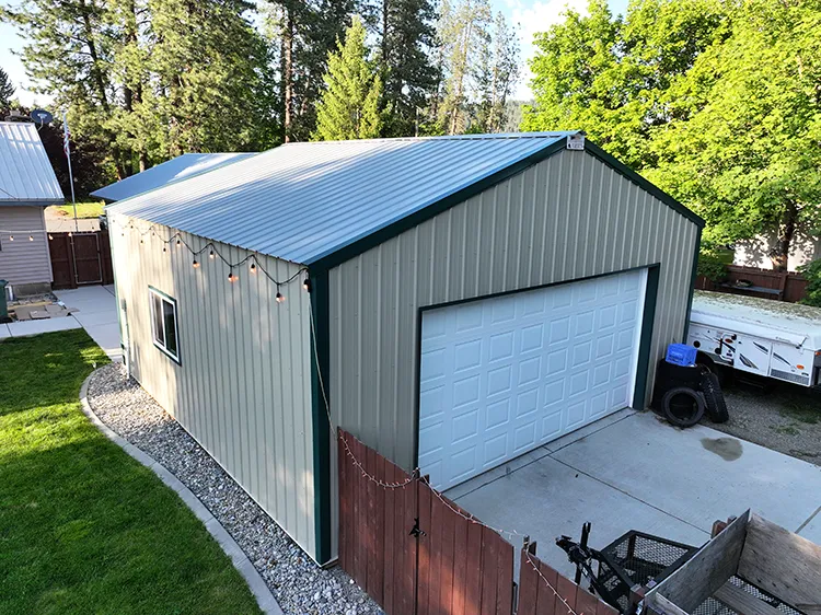 A 2 car pole barn garage that is tan in color with a white overhead door