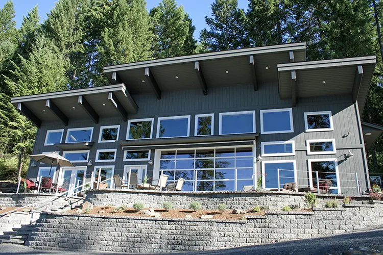 A grey two story barn home with large windows, a common layout for barn homes with living space above
