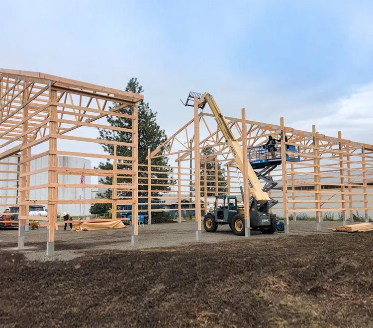 Post-frame wood framing going up on a Steel Structures America build, the structural alternative to red iron metal buildings