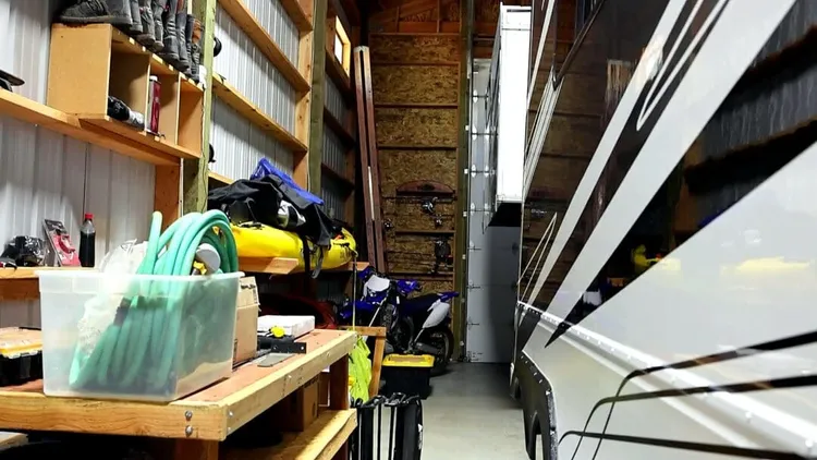 Interior RV storage bay with a kayak, motorcycles, and shelving, the kind of layout RV garage builders plan for