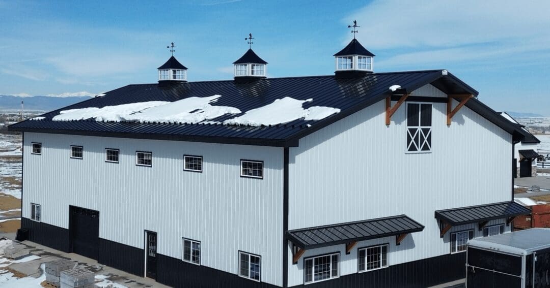 A barndominium that looks like a farmhouse, with a covered porch, gable accents, and a metal roof