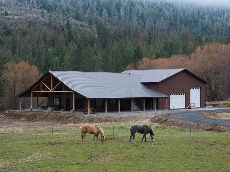 Two horses grazing outside a custom horse barn with living quarters and pole building
