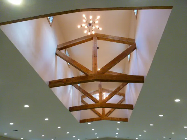 A standard roof truss for a post frame building leaning against lumber, the common shape a gambrel truss departs from