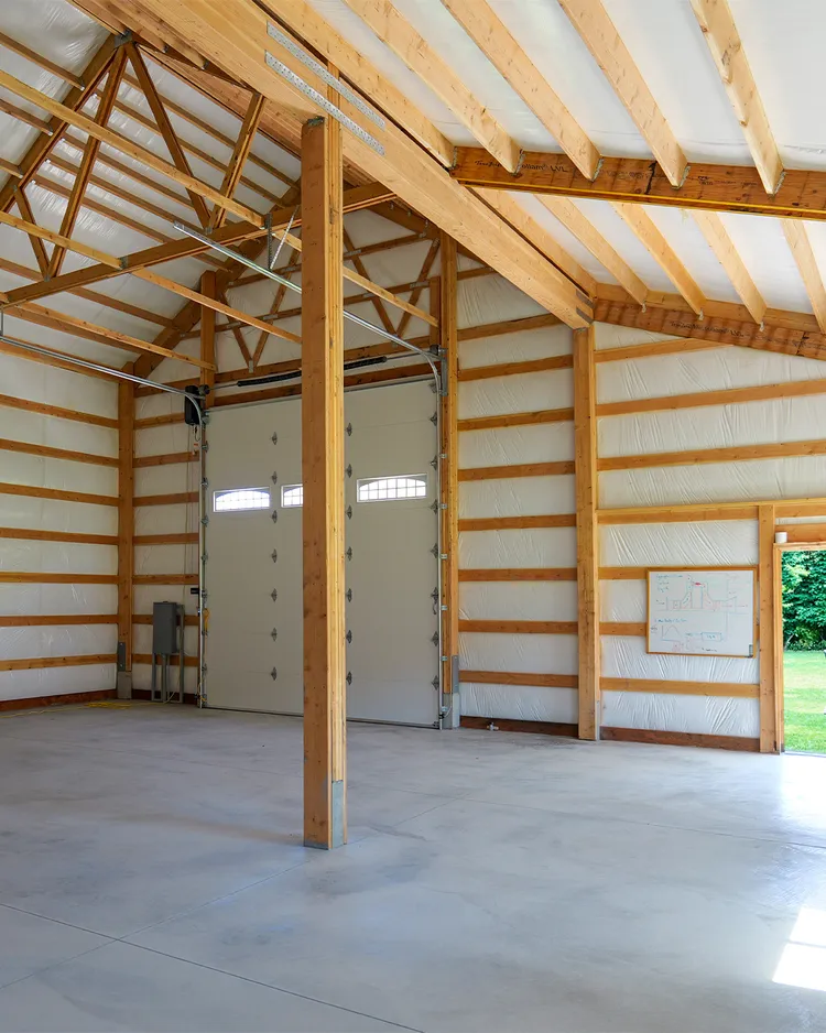 Pole barn trusses spanning a post-frame building, where the truss profile sets a 4/12 roof pitch